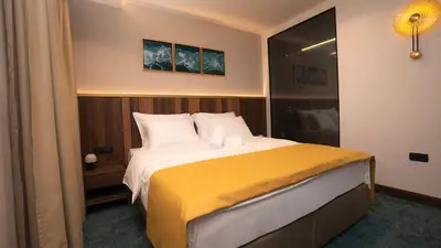 a bedroom with a large bed with a yellow blanket at Hotel Central in Inđija