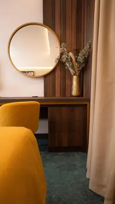 a mirror sitting on a desk with a yellow chair at Hotel Central in Inđija