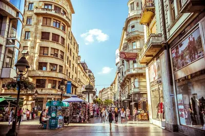 a group of people walking down a street with tall buildings at Belgrade center studio apartment in Belgrade
