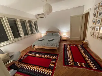 a bedroom with a bed and two large windows at Nomad and Home apartment in Belgrade