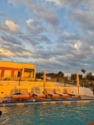 a group of chairs and a pool with a yellow building at Casa Toleni in Ba°evac