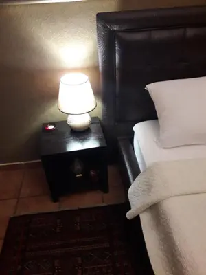 a lamp on a night stand next to a bed at Verdi Apartment in Belgrade