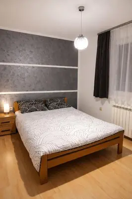 a bedroom with a bed with a gray wall at Apartman LAV in Belgrade