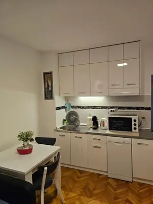 a kitchen with white cabinets and a table and a table and a tableablish at Aker in Belgrade