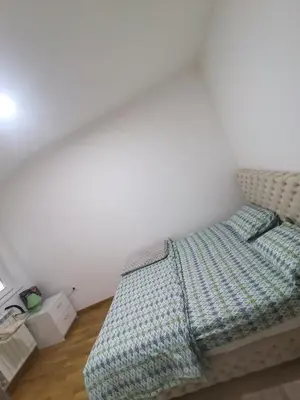 an unmade bed in a room with a white wall at Stan na dan Lux Stara Pazova in Stara Pazova
