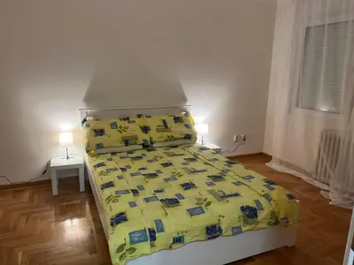 a bedroom with a bed with a yellow comforter and two lamps at Mila in Belgrade