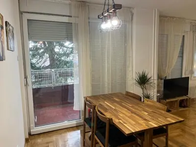a dining room with a wooden table and a window at Mila in Belgrade