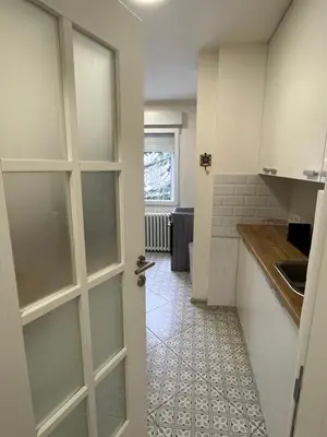 a kitchen with white cabinets and a door at Mila in Belgrade