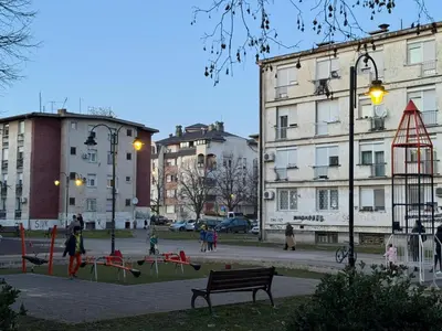 a park with a bench in a city with buildings at Centar Lux Obrenovac, Na Trgu, Siguran Parking in Obrenovac