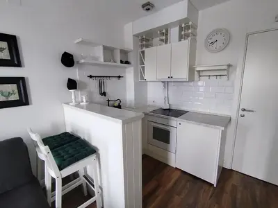 a small kitchen with white cabinets and a green stool at Benvenuti SUN in Belgrade