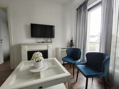 a living room with two blue chairs and a tv at Benvenuti SUN in Belgrade