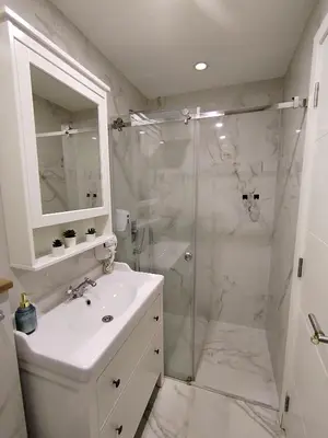 a white bathroom with a shower and a sink at Benvenuti SUN in Belgrade