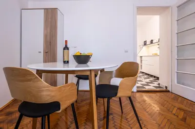 a kitchen with a table with chairs and a bottle of wine at City Center Suites, Two Connected Apartments, 10 Guests in Belgrade