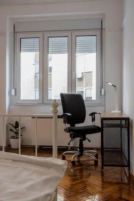 a desk and a chair in a room with windows at City Center Suites, Two Connected Apartments, 10 Guests in Belgrade