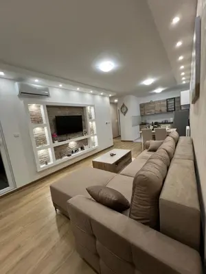 a living room with a large couch and a television at Gold Star Apartman in Ruma