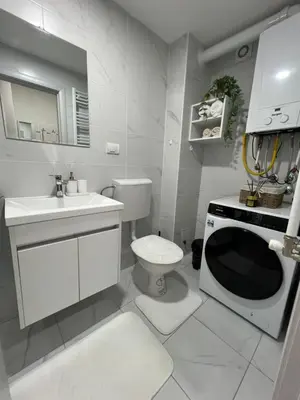 a white bathroom with a toilet and a sink at Gold Star Apartman in Ruma