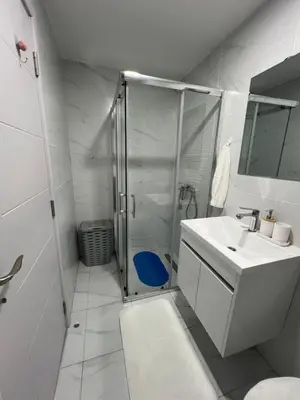 a white bathroom with a shower and a sink at Gold Star Apartman in Ruma