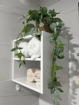 a shelf with towels and a potted plant at Gold Star Apartman in Ruma