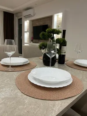 a table with two white plates and wine glasses at Gold Star Apartman in Ruma