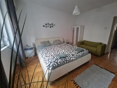 a bedroom with a bed and a green chair at Urban Stay Balkanska in Belgrade