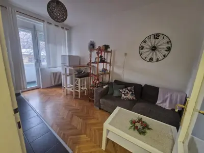 a living room with a couch and a clock on the wall at Urban Stay Balkanska in Belgrade