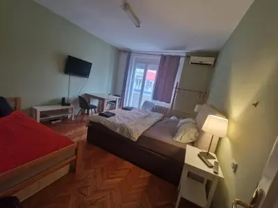 a bedroom with a bed and a desk and a window at Urban Stay Balkanska in Belgrade