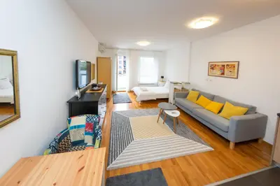 a living room with a gray couch and yellow pillows at Osmica New Belgrade in Bežanija