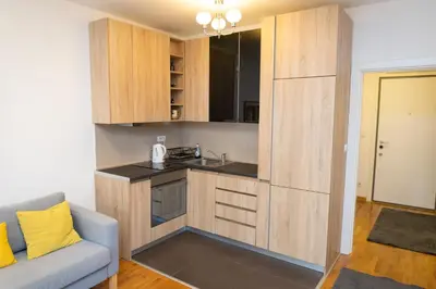 a kitchen with wooden cabinets and a couch in a room at Osmica New Belgrade in Bežanija