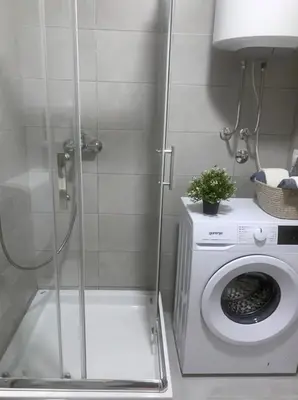 a shower in a bathroom with a washing machine at Aura Apartment - with Garage Parking in Belgrade