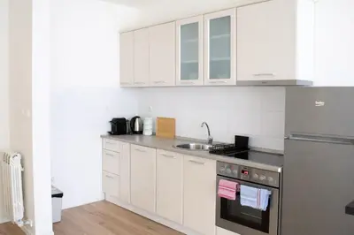 a kitchen with white cabinets and a sink at Aura Apartment - with Garage Parking in Belgrade