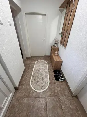 a hallway with a white door and shoes on the floor at Apartman Tas in Smederevo