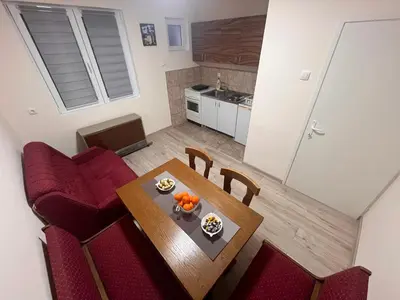 a kitchen and dining room with a table and red chairs at Apartman Tas in Smederevo