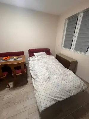 a small bedroom with a bed and a table at Apartman Tas in Smederevo