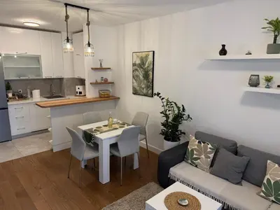 a living room and kitchen with a table and a couch at Garden Escape Zemun in Belgrade