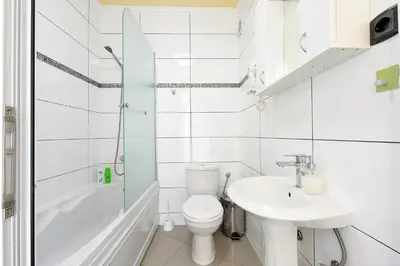 a white bathroom with a toilet and a sink at Apartments Villa Graf in Smederevo