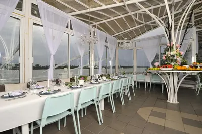 a dining room with white tables and chairs and windows at Apartments Villa Graf in Smederevo