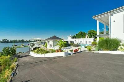 a large white house with a driveway next to the water at Apartments Villa Graf in Smederevo