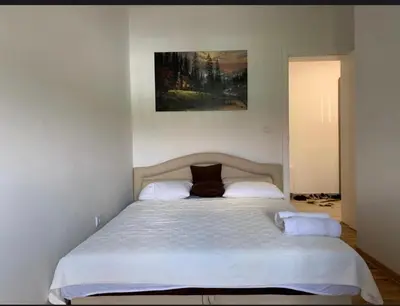a bed in a bedroom with a painting on the wall at Royal Residence aprtamani Aviv in Pančevo