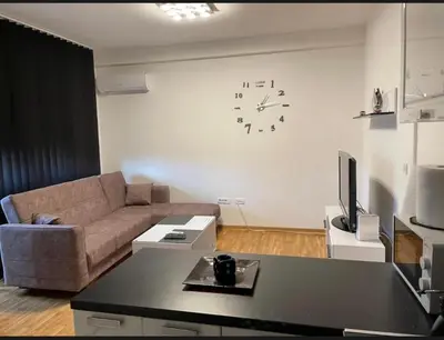 a living room with a couch and a clock on the wall at Royal Residence aprtamani Aviv in Pančevo