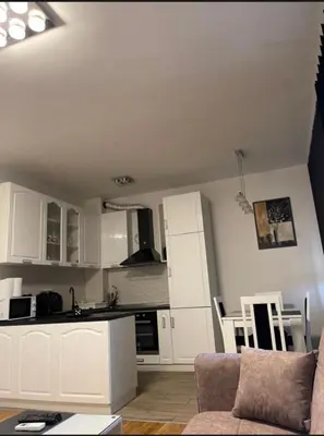 a kitchen with white cabinets and a couch in a room at Royal Residence aprtamani Aviv in Pančevo