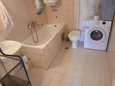 a bathroom with a tub and a toilet and a washing machine at Apartman86 in Beograd