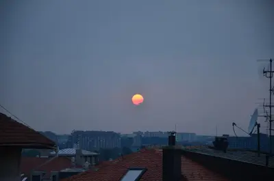 a sun in the sky over a city with roofs at casa CIUK in Belgrade
