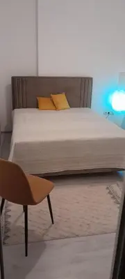 a bed with yellow pillows and a chair in a room at Flat center of Belgrade in Belgrade