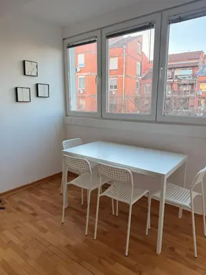 a white table and chairs in a room with windows at Light & Cozy Flat Banovo Brdo in Belgrade