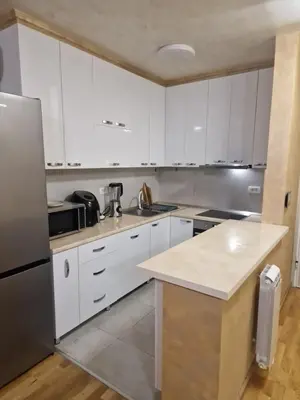 a kitchen with white cabinets and a stainless steel refrigerator at Apartman Oskar Dunav in Stari Banovci