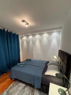a bedroom with a blue bed and blue curtains at Apartman Sasha 3 - Free parking in Belgrade