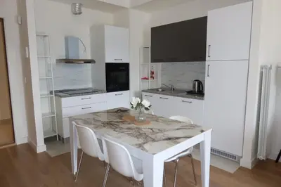 a white kitchen with a marble table and white chairs at Beograd na vodi Belgrade waterfront - Great city view in Belgrade