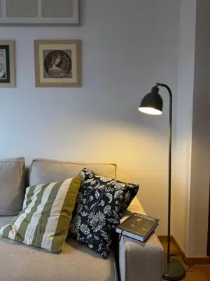 a lamp sitting next to a couch with a pillow at DUMA Apartmani Arandjelovac in Arandjelovac