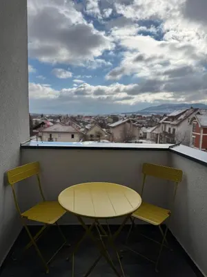 a yellow table and two chairs on a balcony with a view at DUMA Apartmani Arandjelovac in Arandjelovac