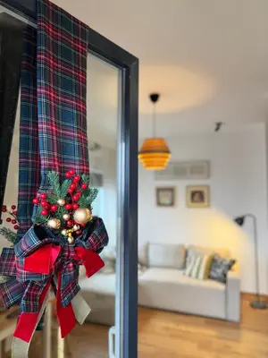 a christmas bow on a curtain in a living room at DUMA Apartmani Arandjelovac in Arandjelovac